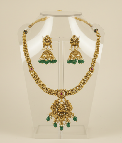 Gold necklace and earrings on a mannequin bust with a beige background