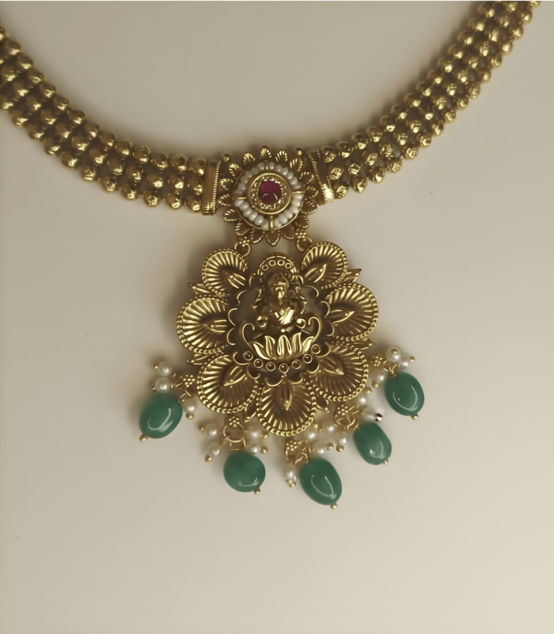 Gold necklace with green beads on a beige background