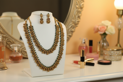 Gold necklace and earrings set on a white stand against a orange background