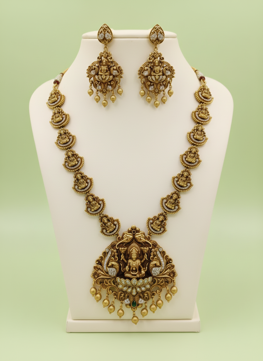 Gold necklace and earrings set on a white stand with a light green background
