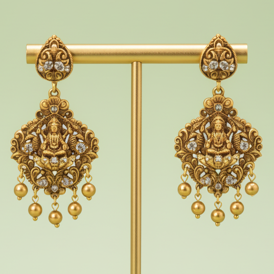 Decorative gold earrings on a matching stand against a light green background