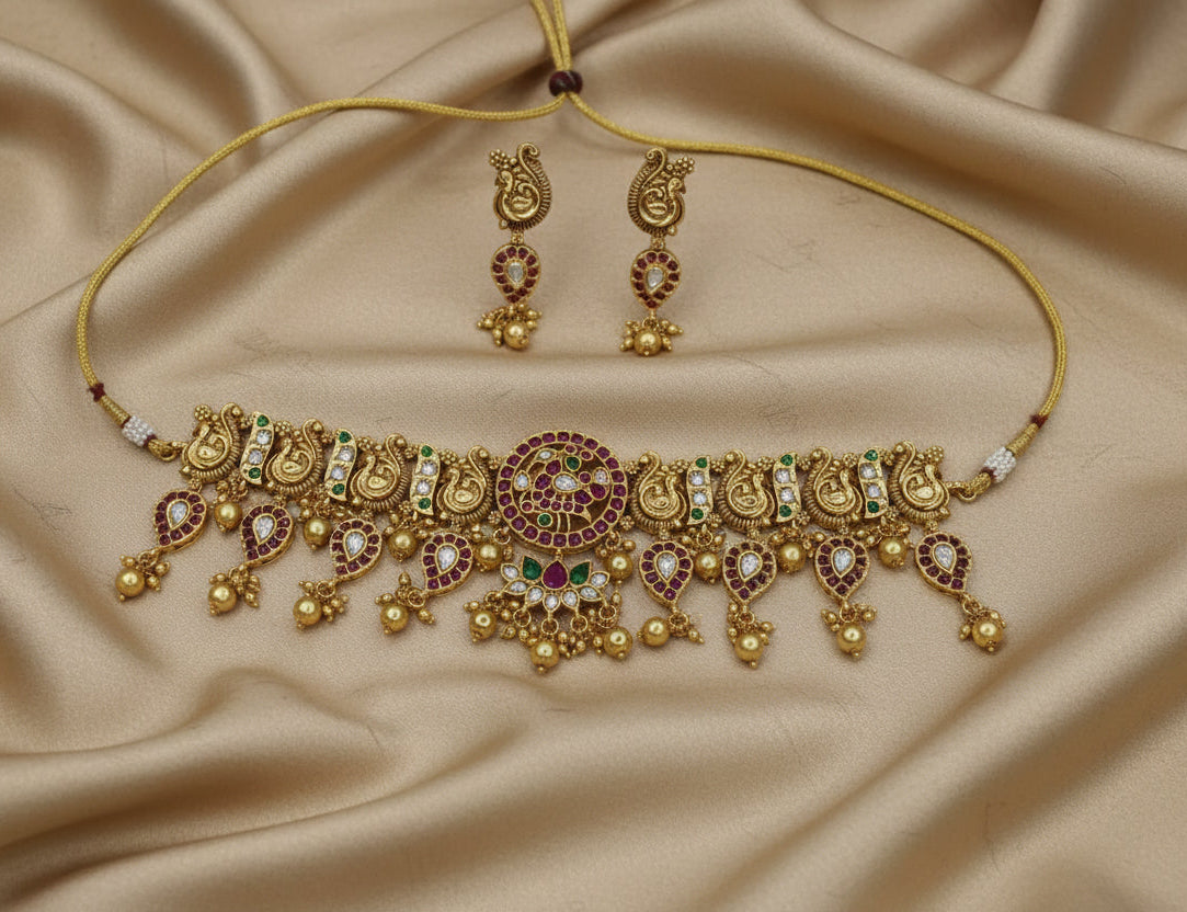 Gold necklace with stones and matching earrings on a beige background
