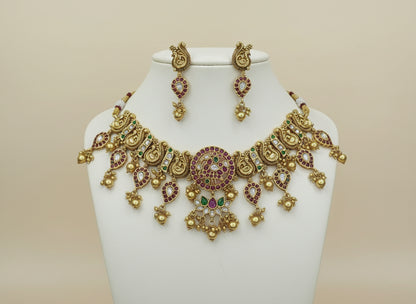 Gold necklace with red and green stones on a white fabric background