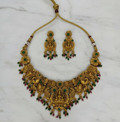 Gold necklace and earrings set on a marble background