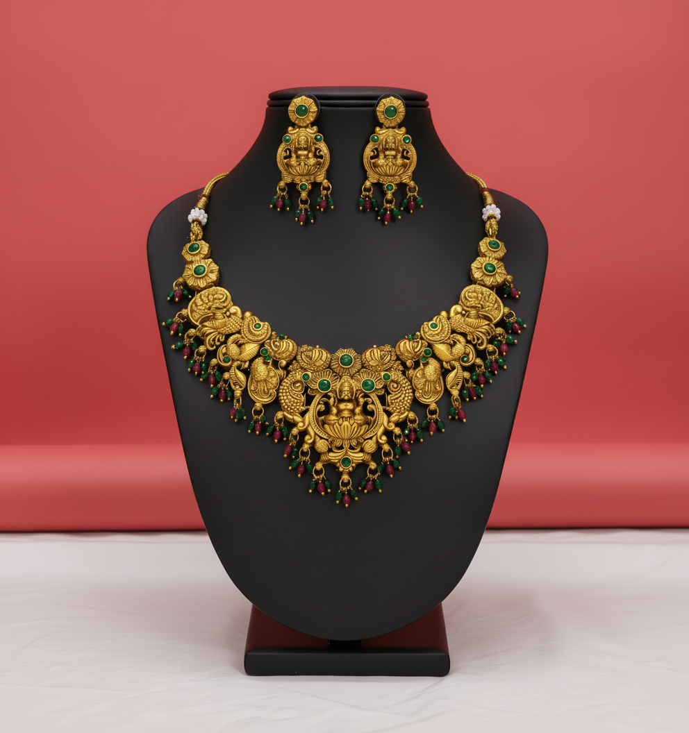 Gold necklace and earrings on a black stand against a red background