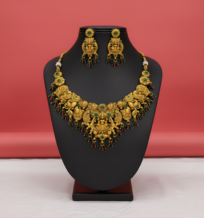 Gold necklace and earrings on a black stand against a red background