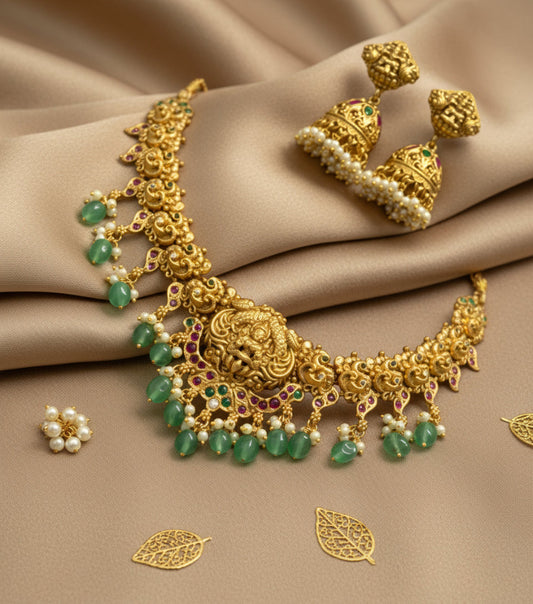 Gold necklace with emeralds and pearls on a beige fabric background