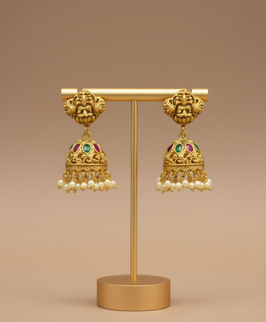 Gold earrings with pearl details on a brown stand