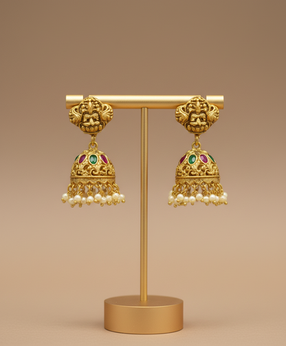 Gold earrings with pearl details on a brown stand