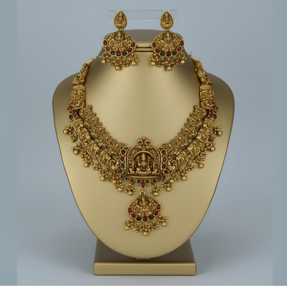 Gold necklace and earrings set on a mannequin bust with a plain background