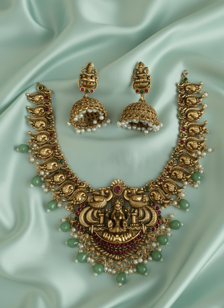 Gold necklace and earrings set on a light blue satin background