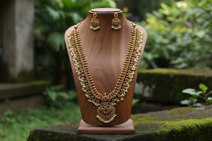 Gold necklace and earrings on a wooden mannequin against a natural background