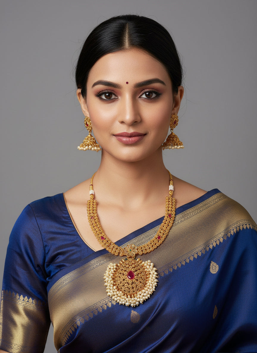 Woman wearing a blue saree with gold jewelry on a gray background
