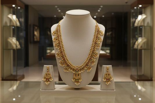 Gold necklace and earrings set on a mannequin bust with a beige background
