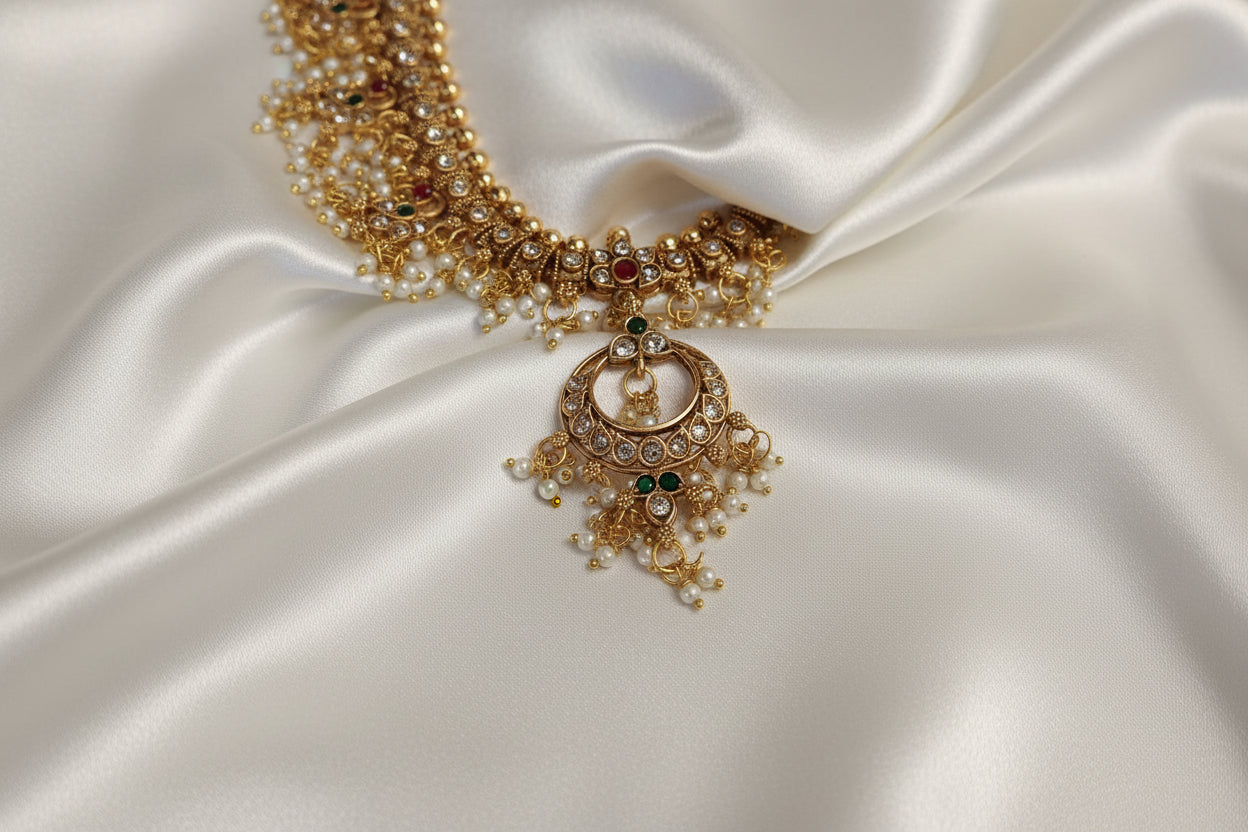Gold necklace with green gemstones on a white satin background