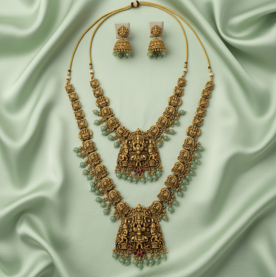 Ornate gold necklace with green beads on a light green fabric background
