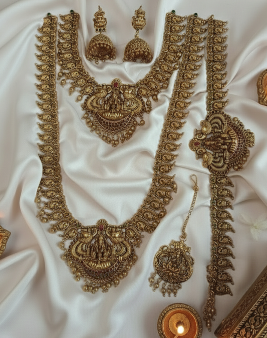 Ornate gold jewelry set on a white fabric background