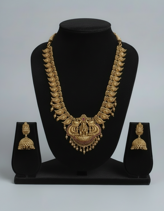 Gold necklace and earrings set on a black stand with a gray background