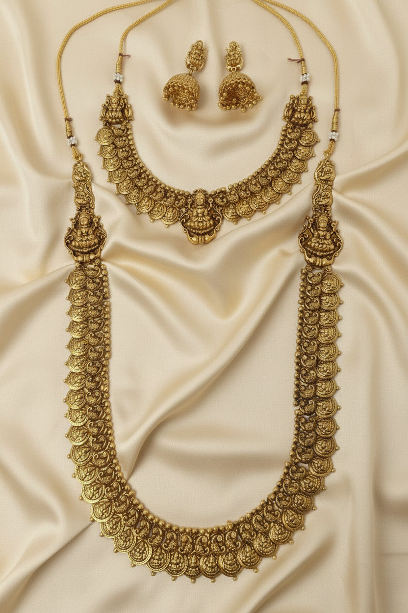 Gold necklace and earrings set on a beige fabric background