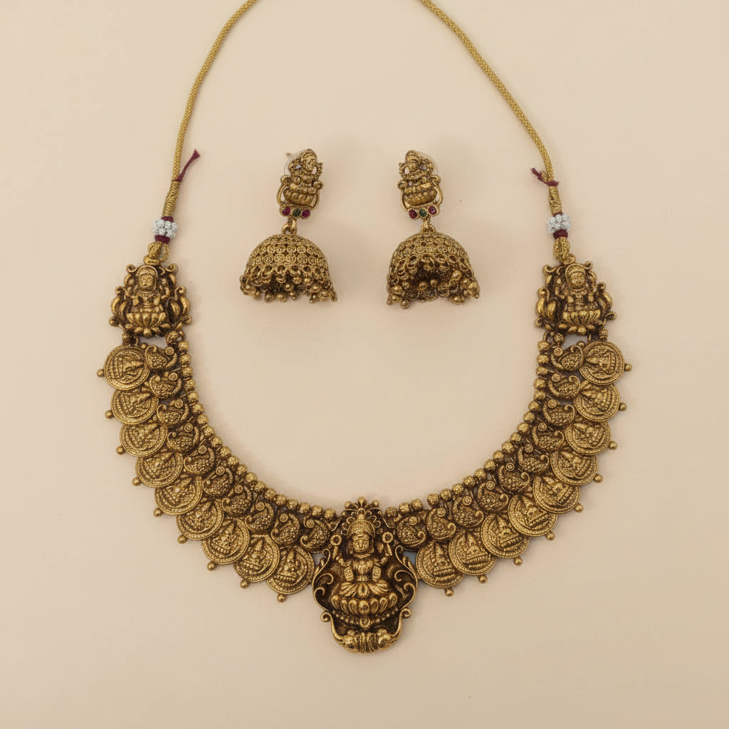 Gold necklace and earrings set on a beige background
