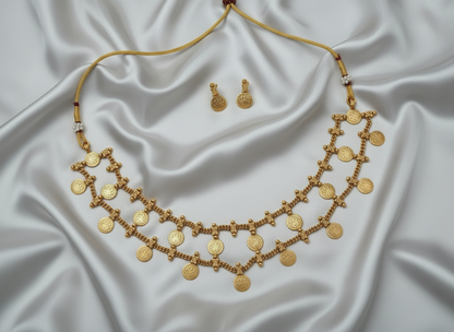Gold necklace and earrings on a white satin background