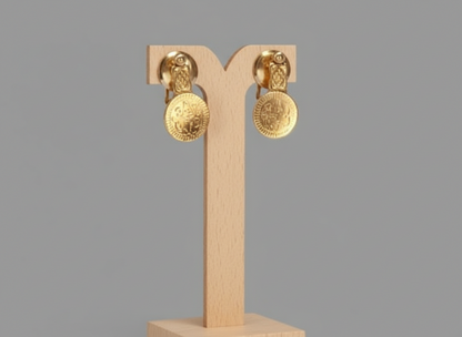 Gold earrings on a wooden display stand against a gray background