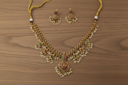 Gold necklace with pearls and gemstones on a beige background