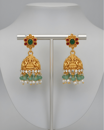 Gold earrings with green and red stones on a white background