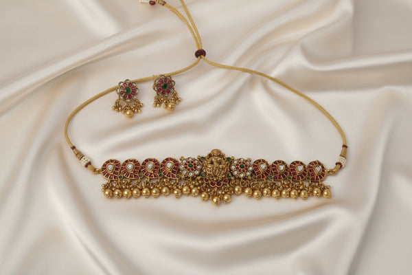 Gold necklace and earrings on a white satin background