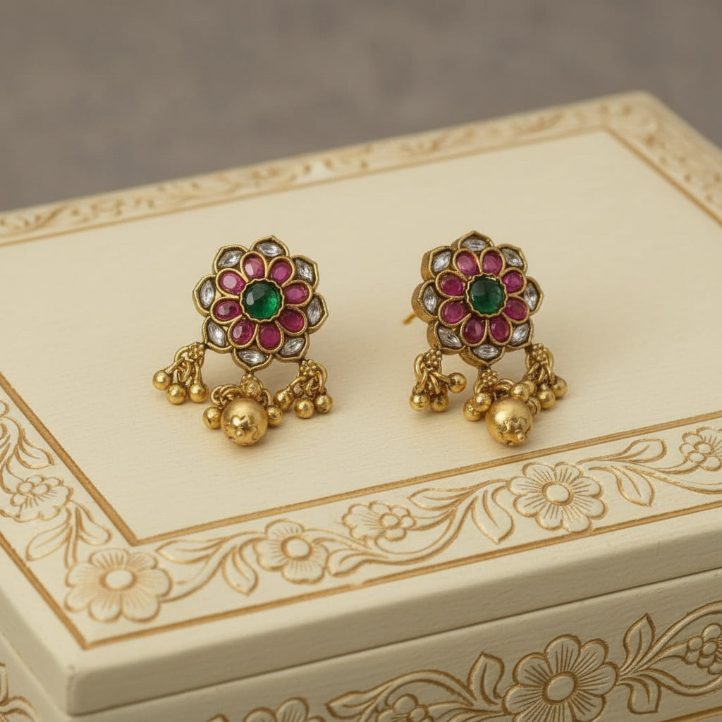 Decorative gold earrings with gemstones on an ornate box