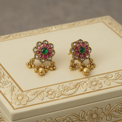 Decorative gold earrings with gemstones on an ornate box