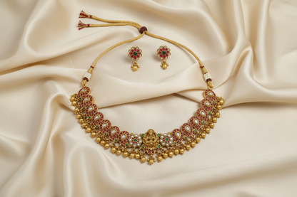 Gold necklace and earrings on a beige fabric background