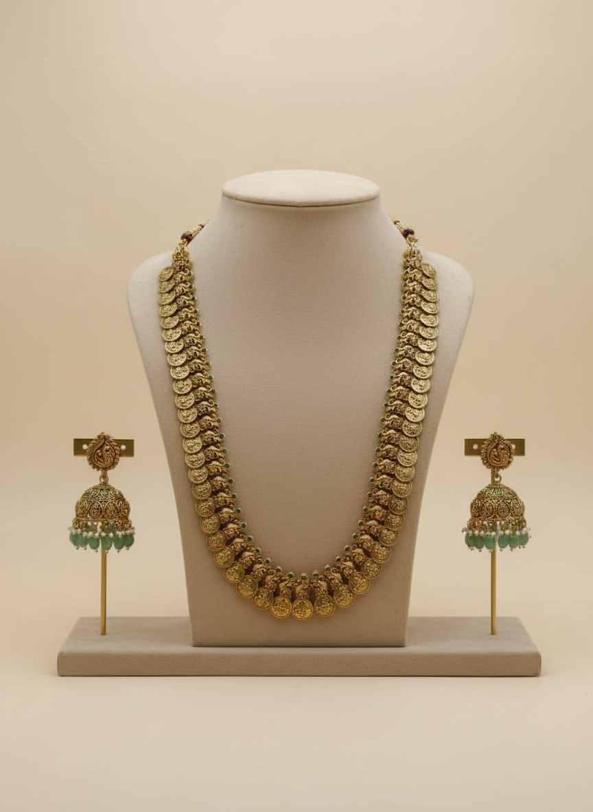 Gold necklace and earrings set on a mannequin bust with a beige background
