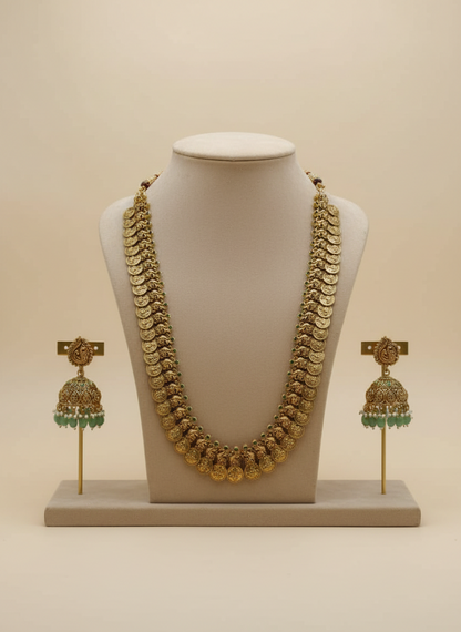 Gold necklace and earrings set on a mannequin bust with a beige background