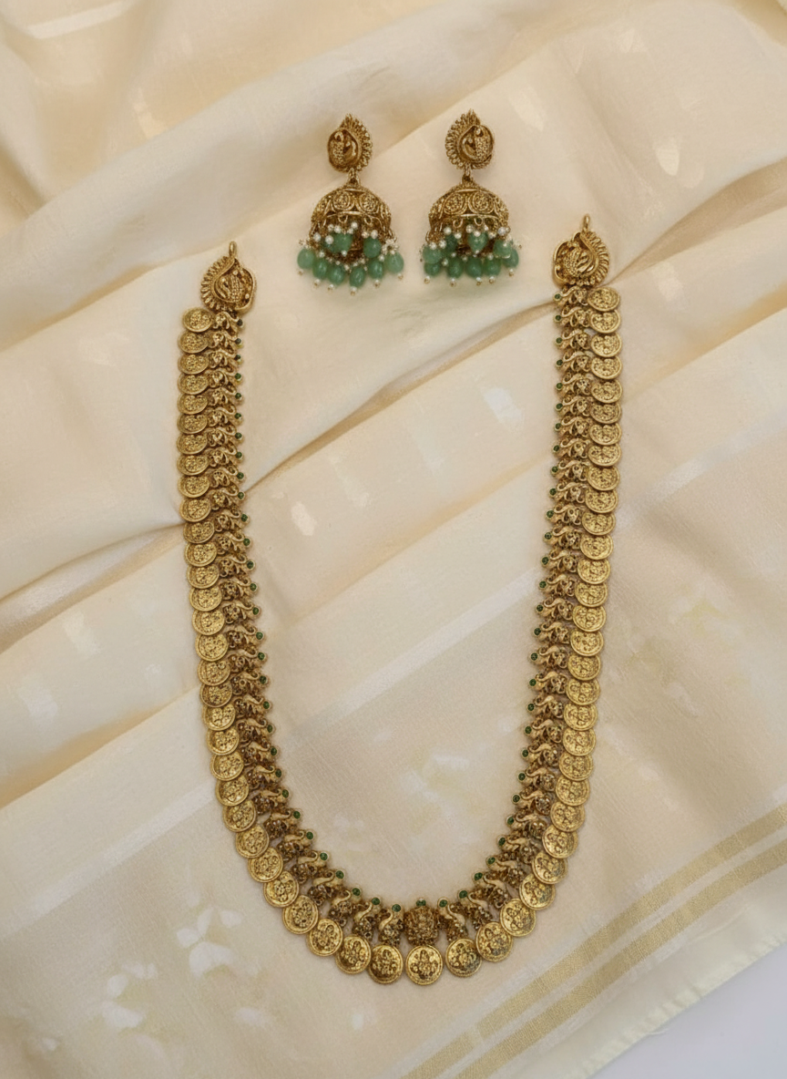 Gold necklace and earrings on a textured beige surface