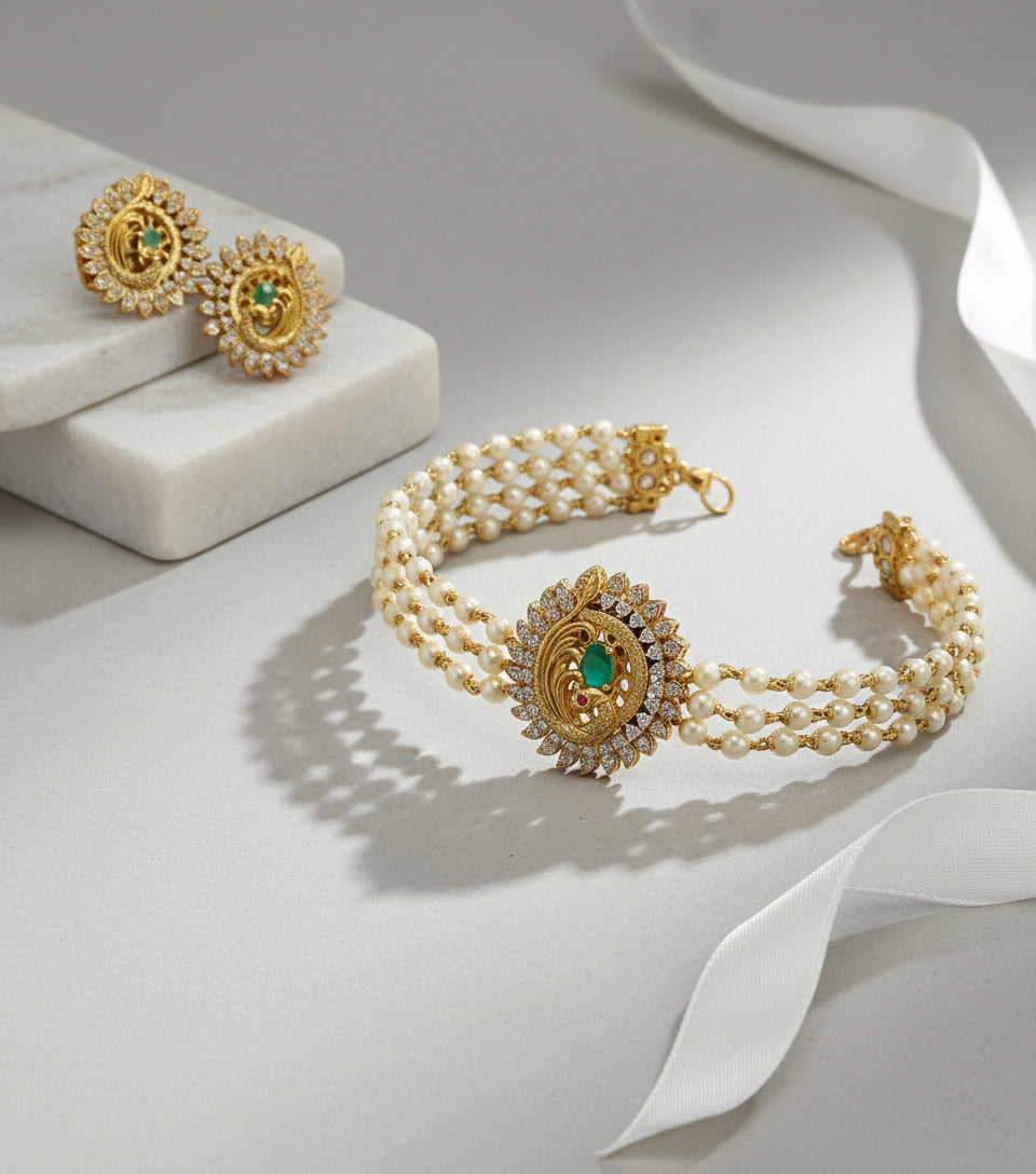 Gold bracelet with green gemstone and pearl accents on a light gray background