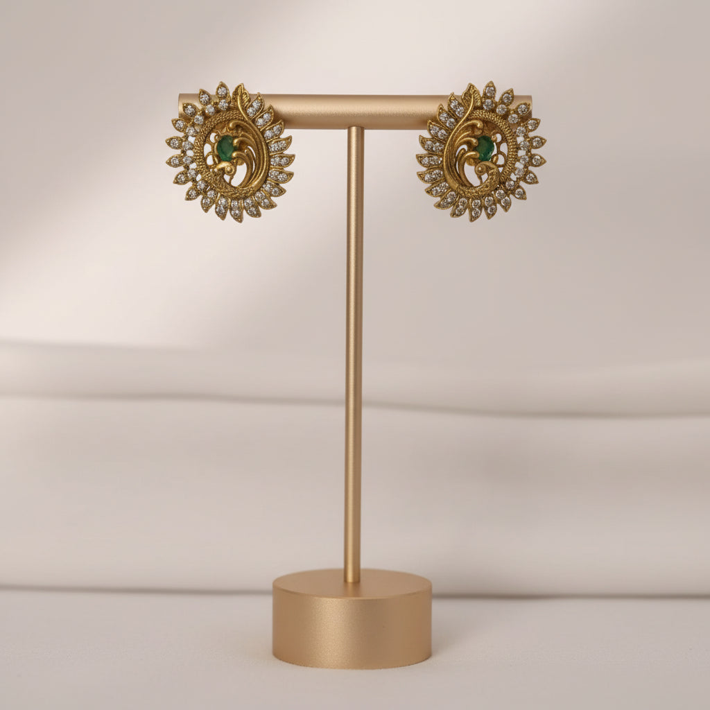 Pair of ornate earrings on a gold stand against a neutral background