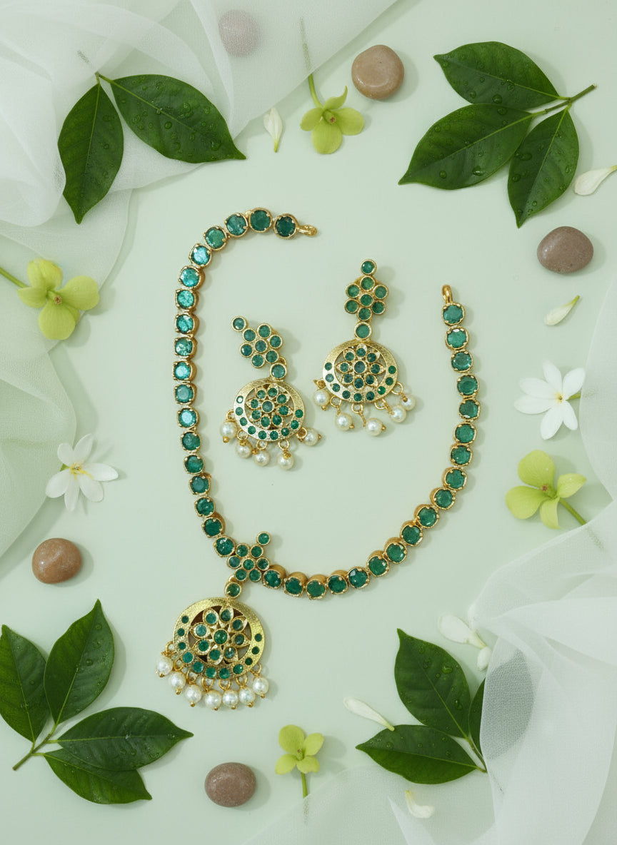 Green and gold jewelry set with leaves and flowers on a light background