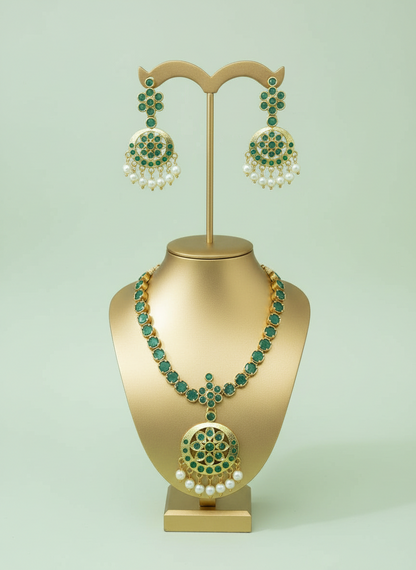 Jewelry set with necklace and earrings on a gold stand against a light green background