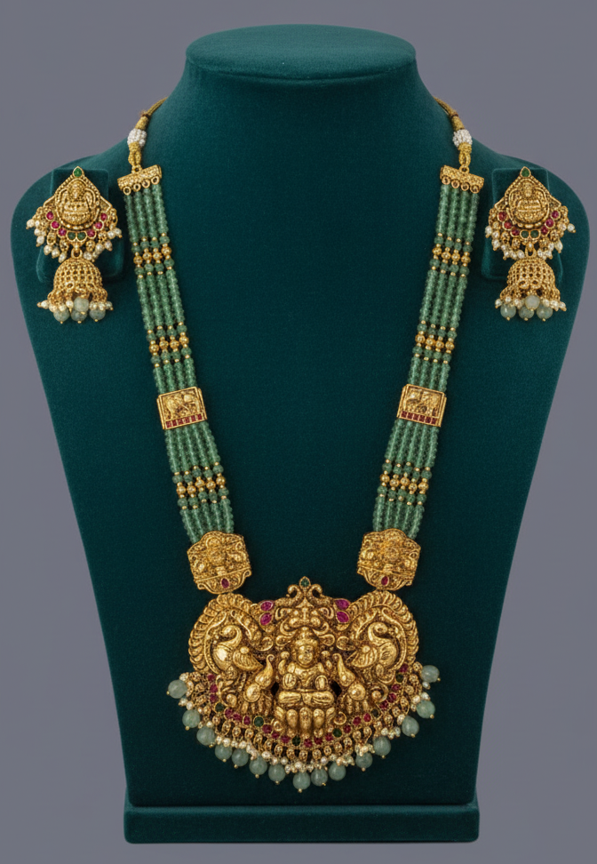 Ornate gold necklace with green beads on a green stand