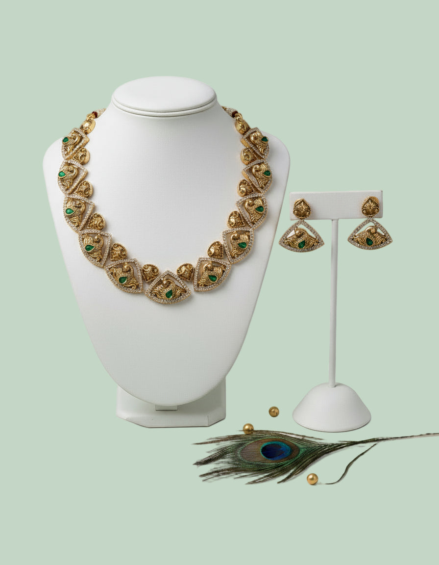 Gold necklace and earrings on a white mannequin with a peacock feather on a light green background