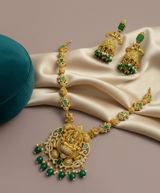 Gold necklace with green gemstones on a beige fabric background