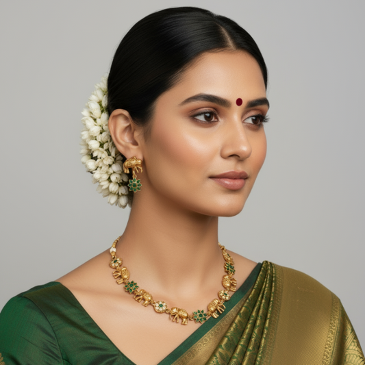 Woman wearing gold jewelry and a green saree against a gray background