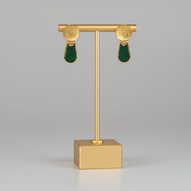 Gold earring stand with green earrings on a gray background