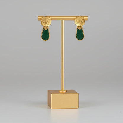 Gold earring stand with green earrings on a gray background