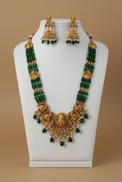 Gold and green beaded necklace set on a mannequin bust against a beige background