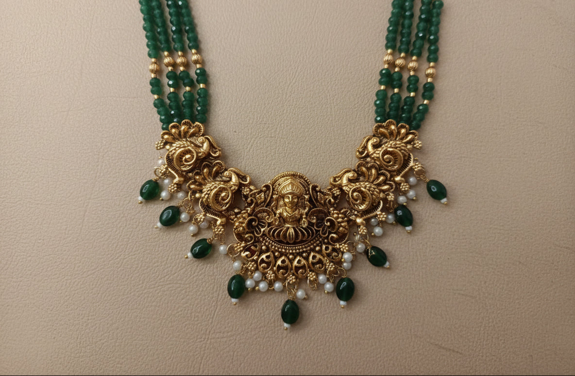 Gold necklace with green and white beads on a beige background