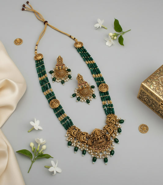 Green and gold necklace set with earrings on a gray background