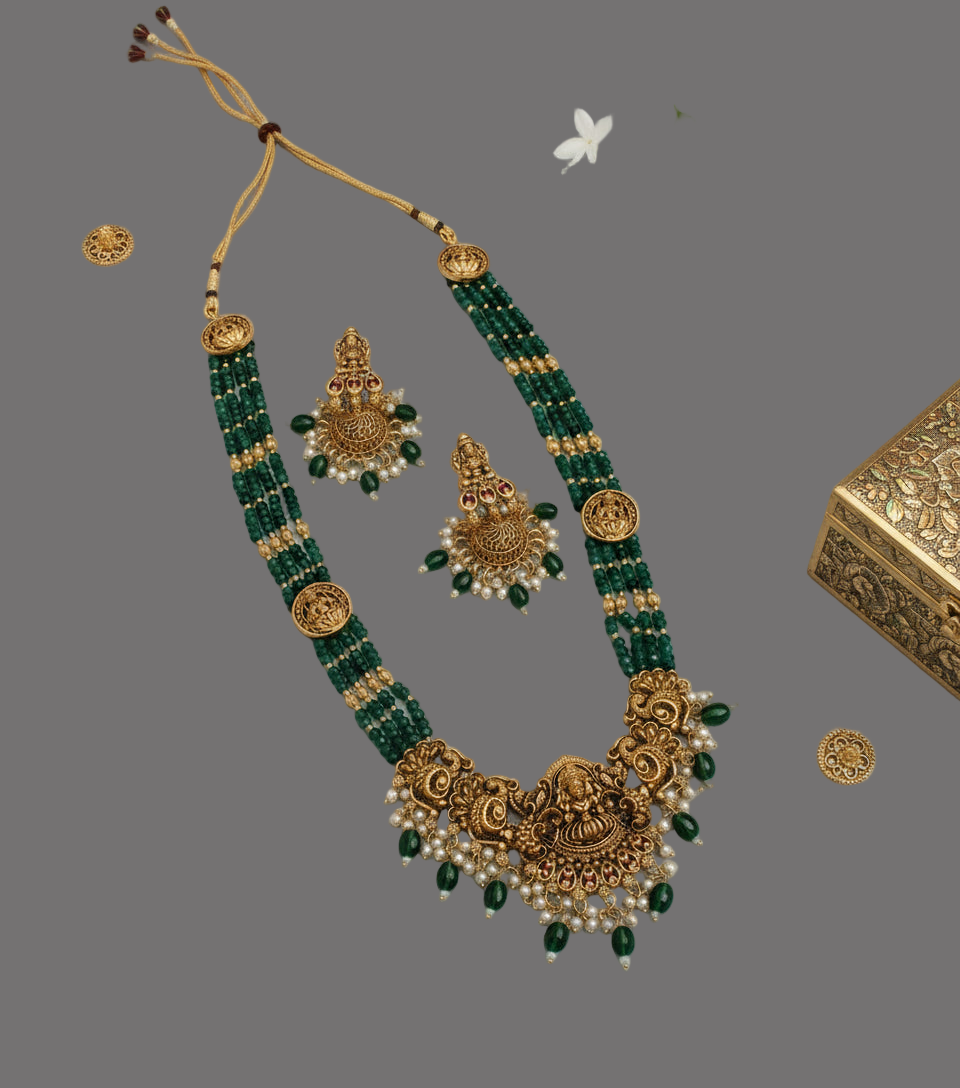 Green and gold necklace set with matching earrings on a gray background