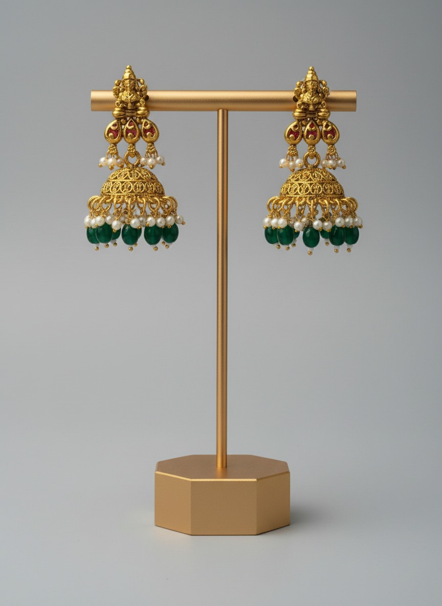 Gold earrings with green and pearl accents on a gold stand against a gray background